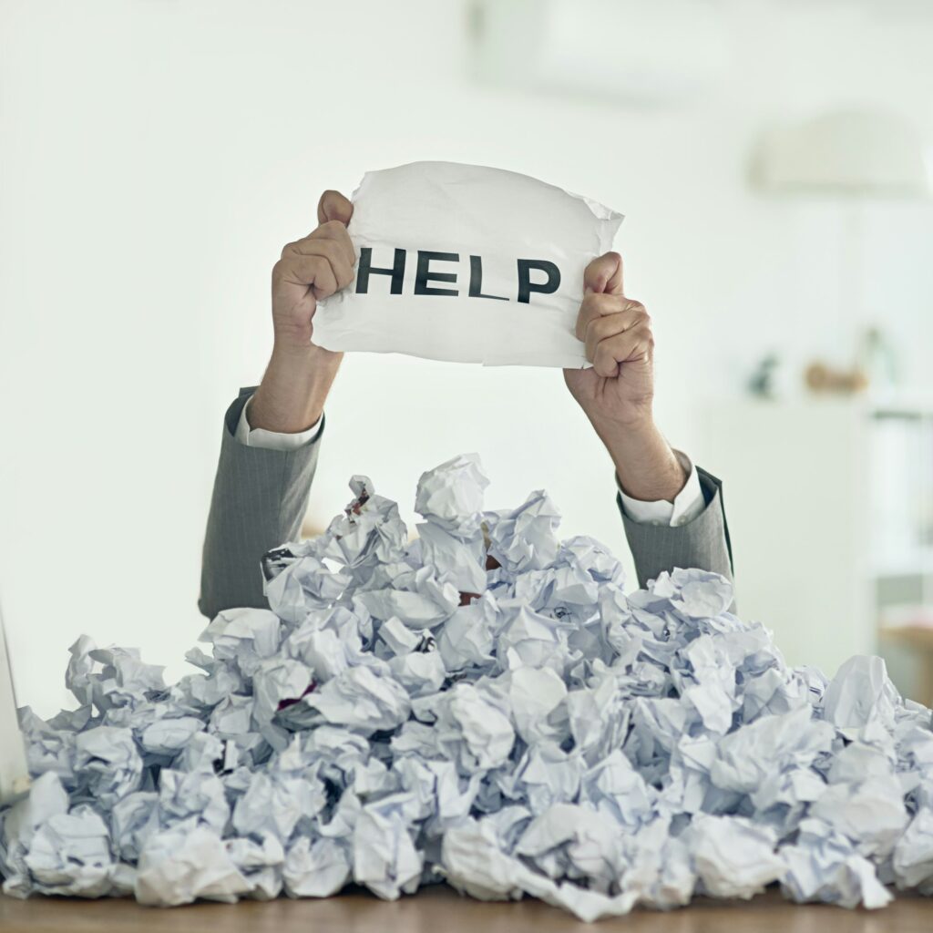 Shot of an unidentifiable businessman drowning under a pile of paperwork in the office
